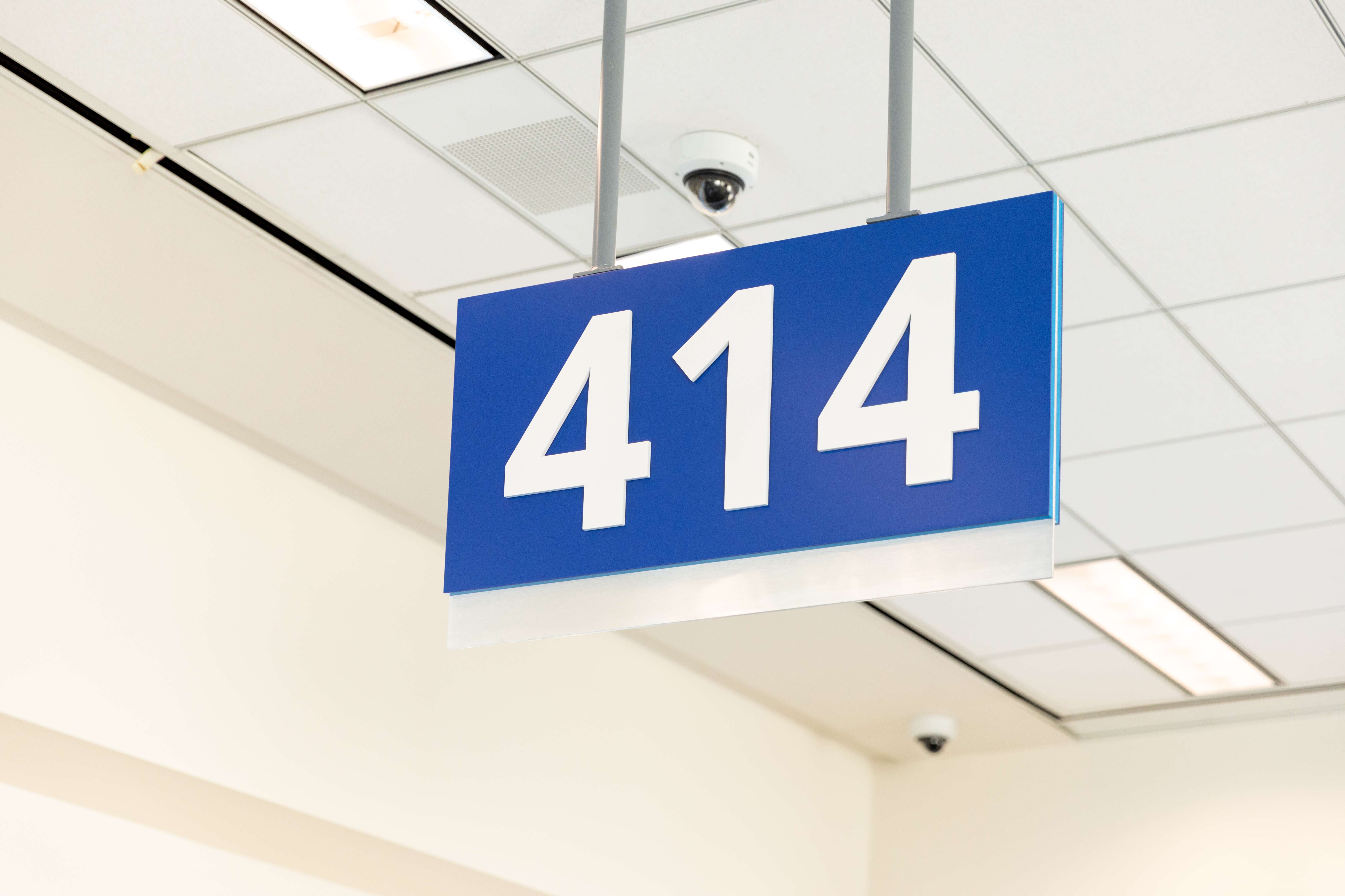 Blue sign with the number 414 hanging from a white ceiling.