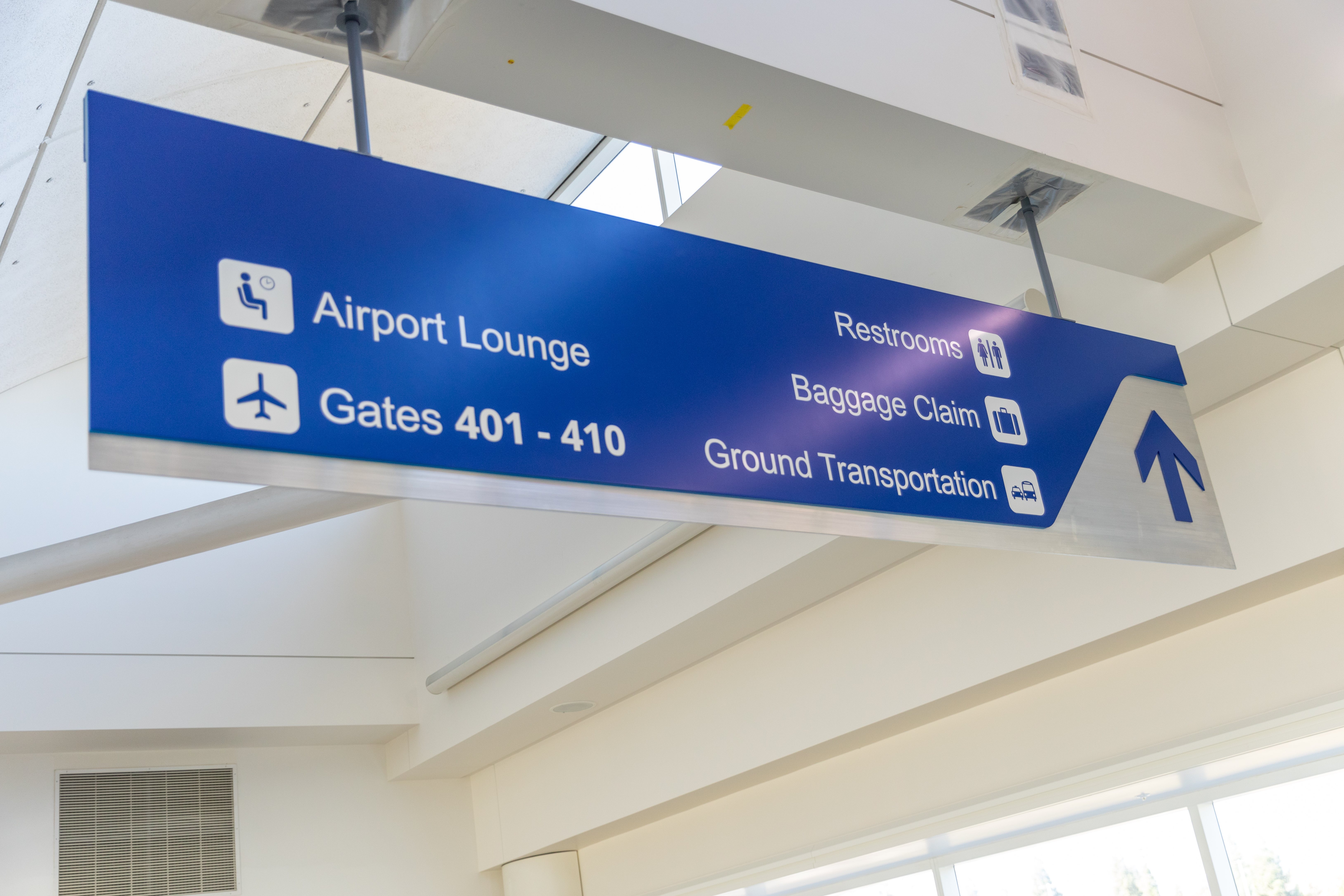Airport directional sign with arrows pointing to Lounge and Gates 401-410.