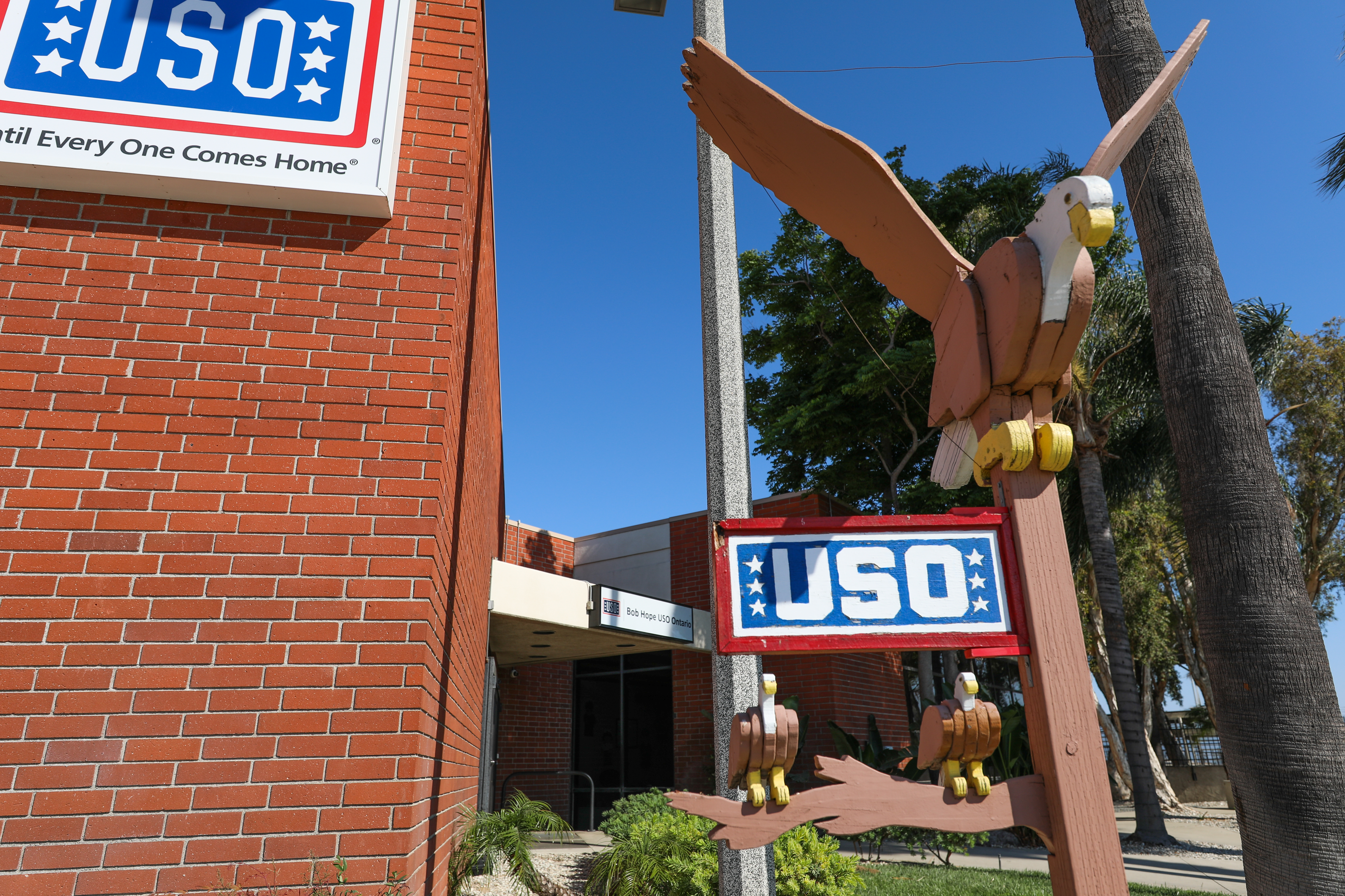 Brick entrance to a USO building with blue signage against a clear sky.