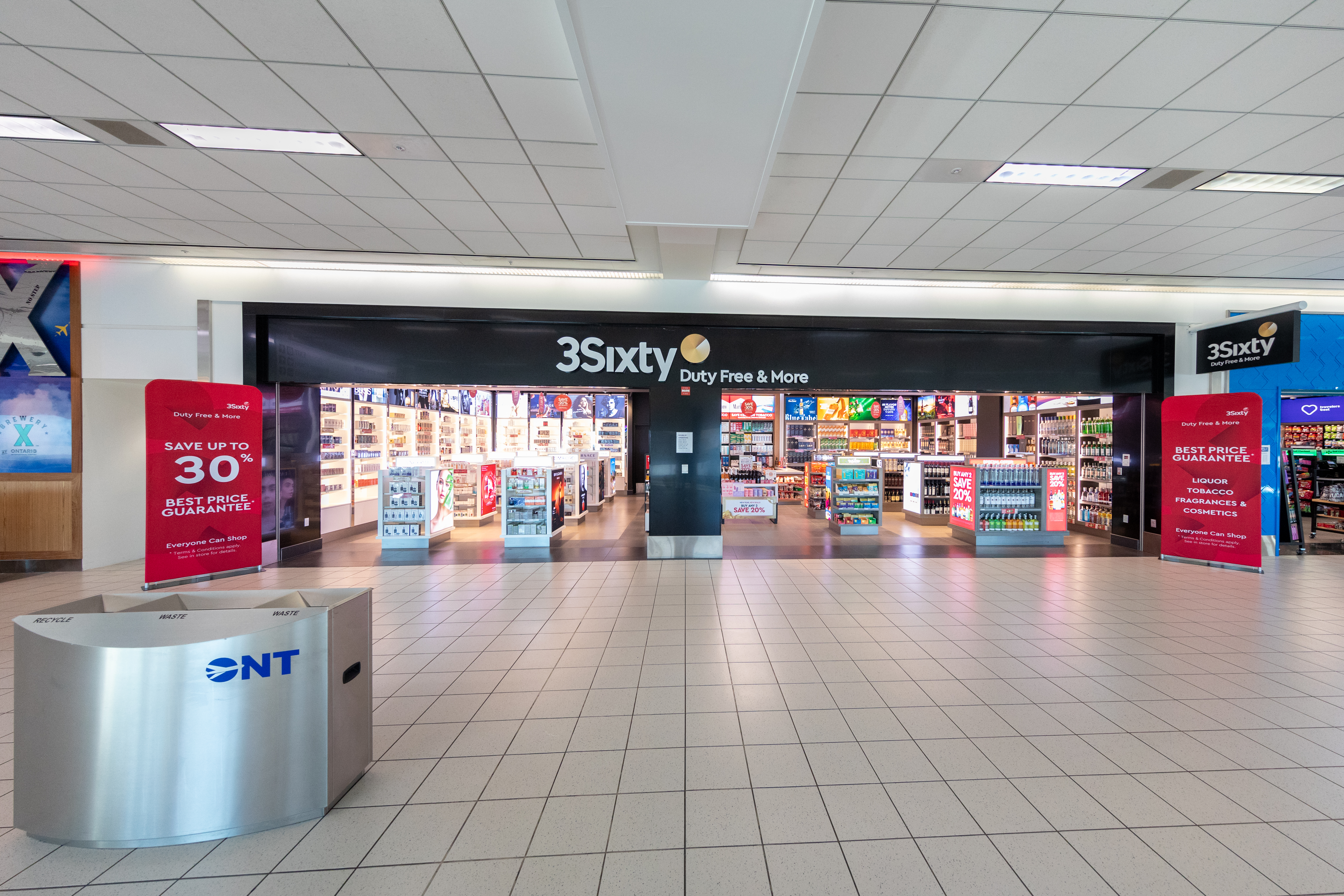 Convenience store entrance with illuminated display inside a bright mall corridor.