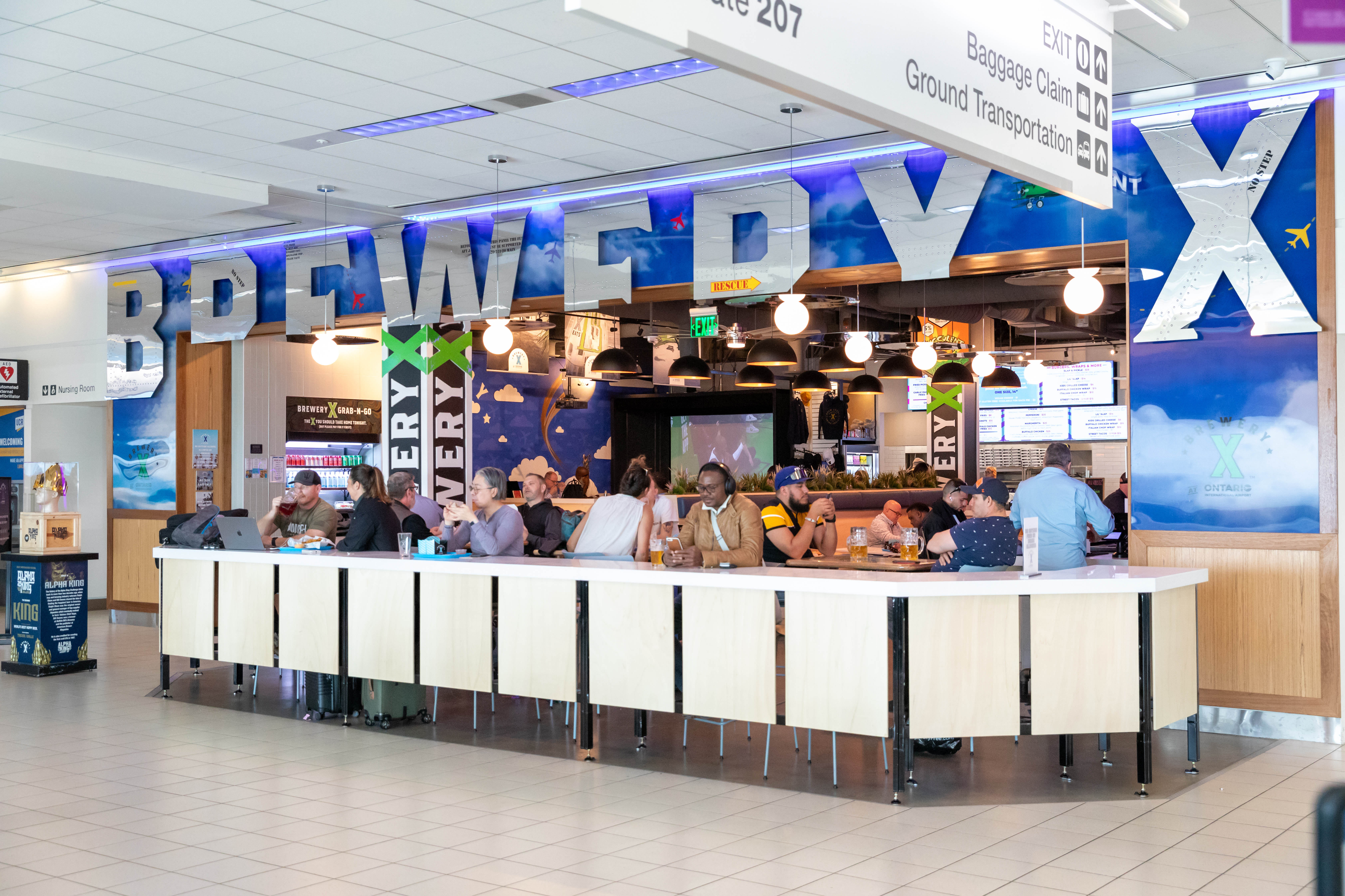 Blue and white Pret A Manger cafe counter in an airport terminal with staff ready to serve.