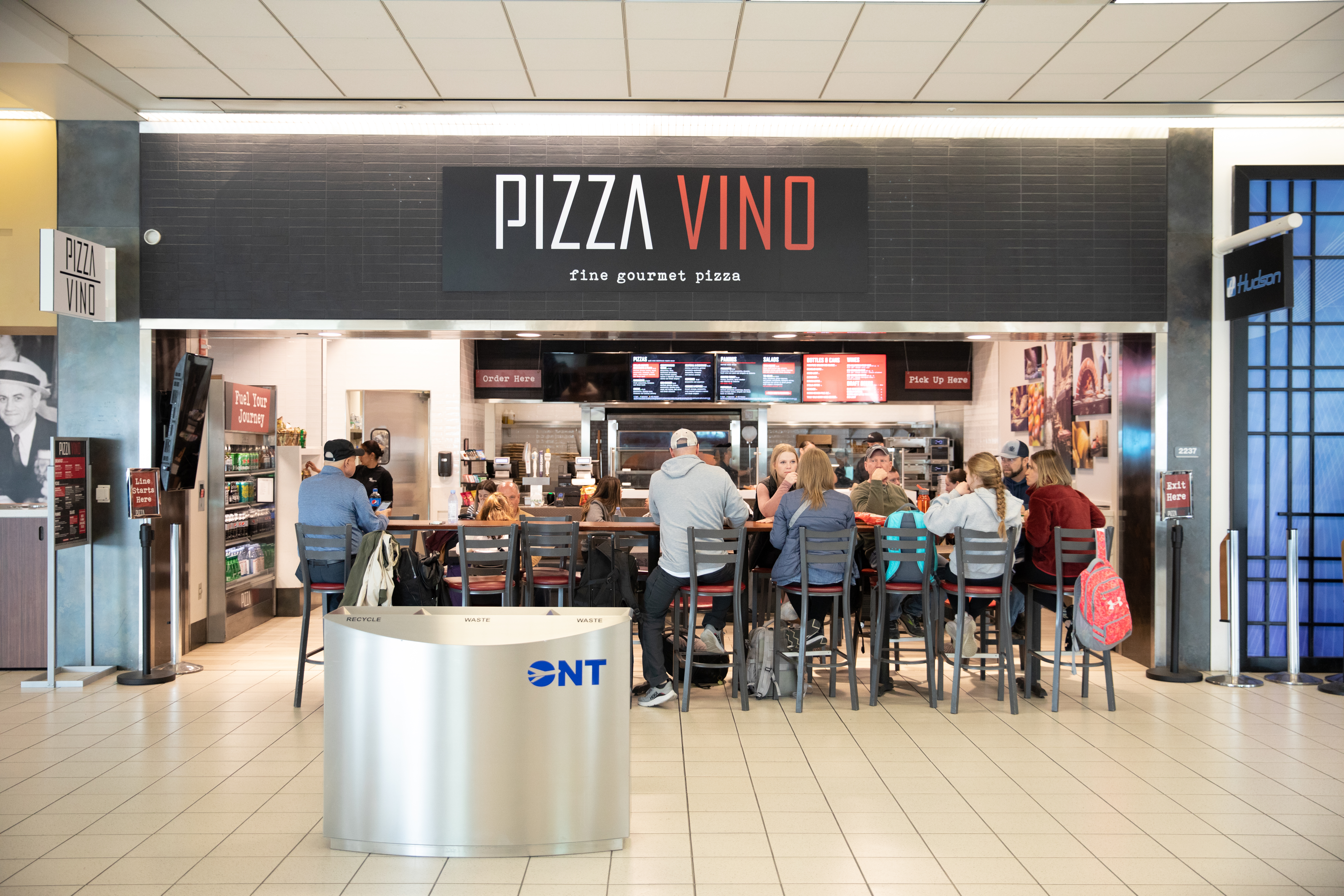 Pizza Vino restaurant storefront with customers seated at tables in a shopping mall.