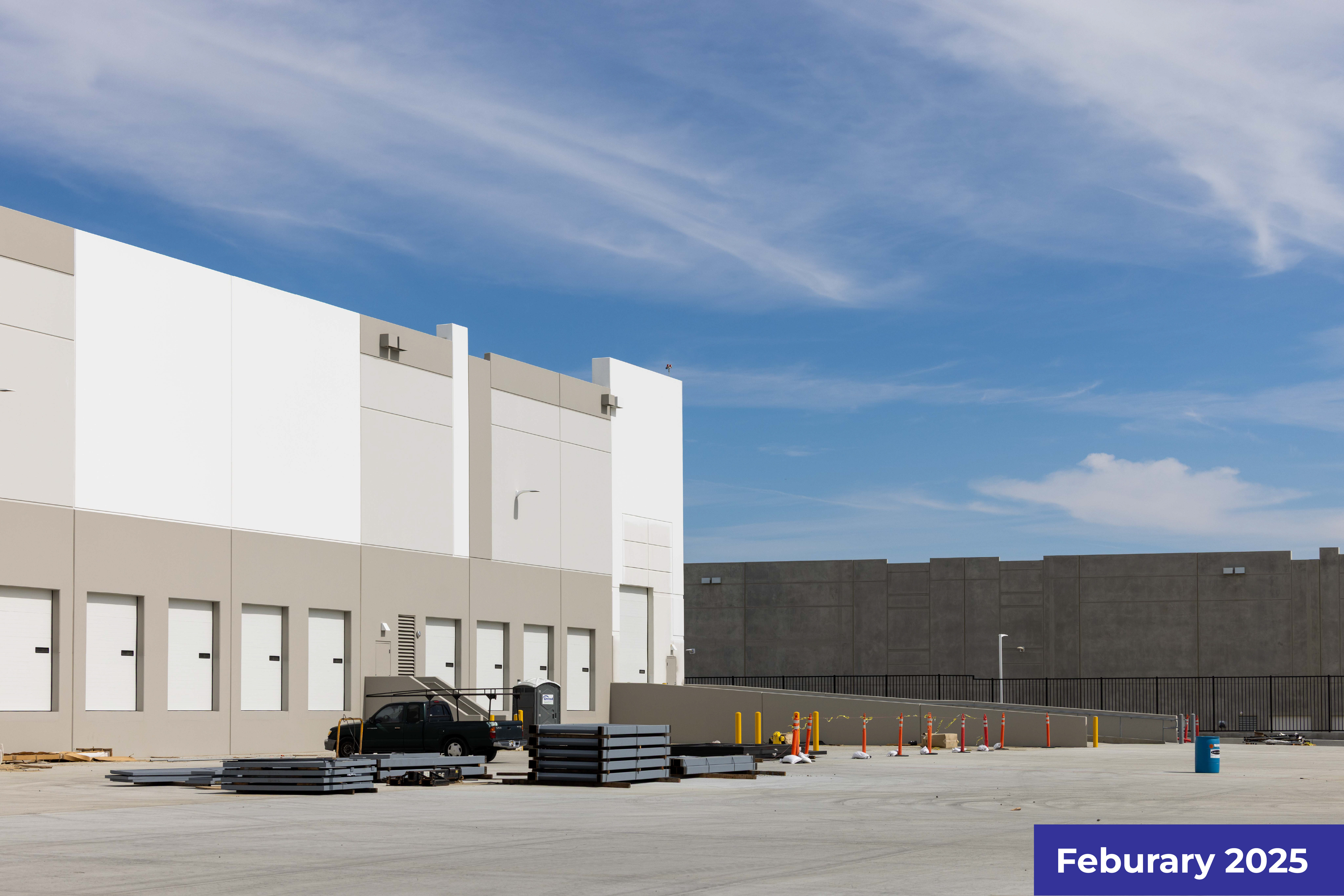 Large warehouse or distribution center with white and gray exterior, parking area visible.