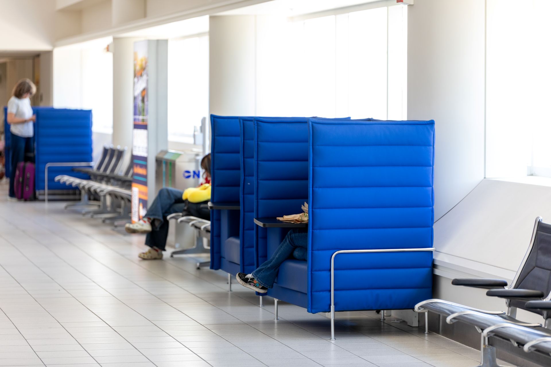 Shoes are seen hanging out of bright blue booths that seat one and have charging stations for passengers.