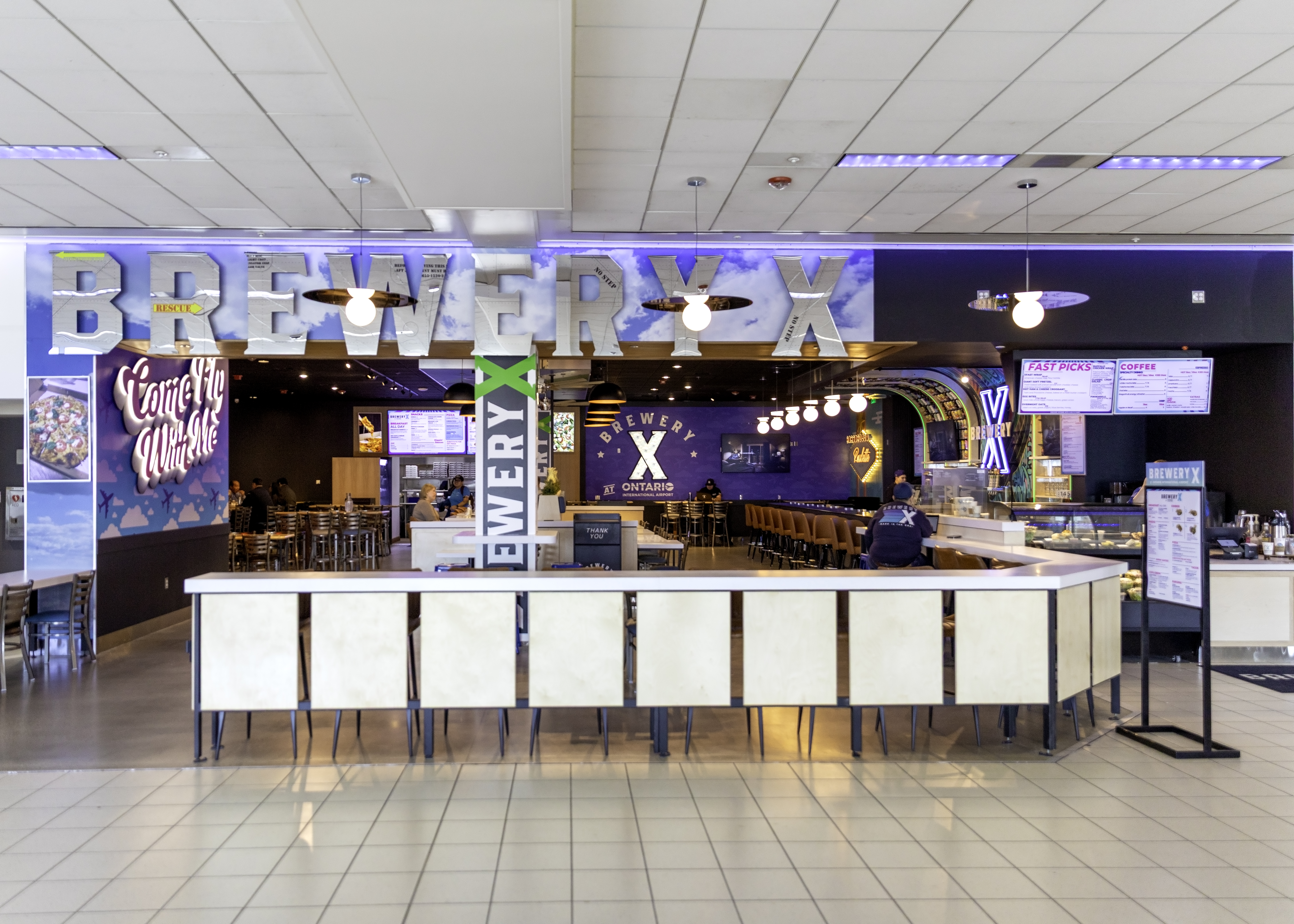 New Brewery X in T4 shows people sitting down behind the front counter.. 