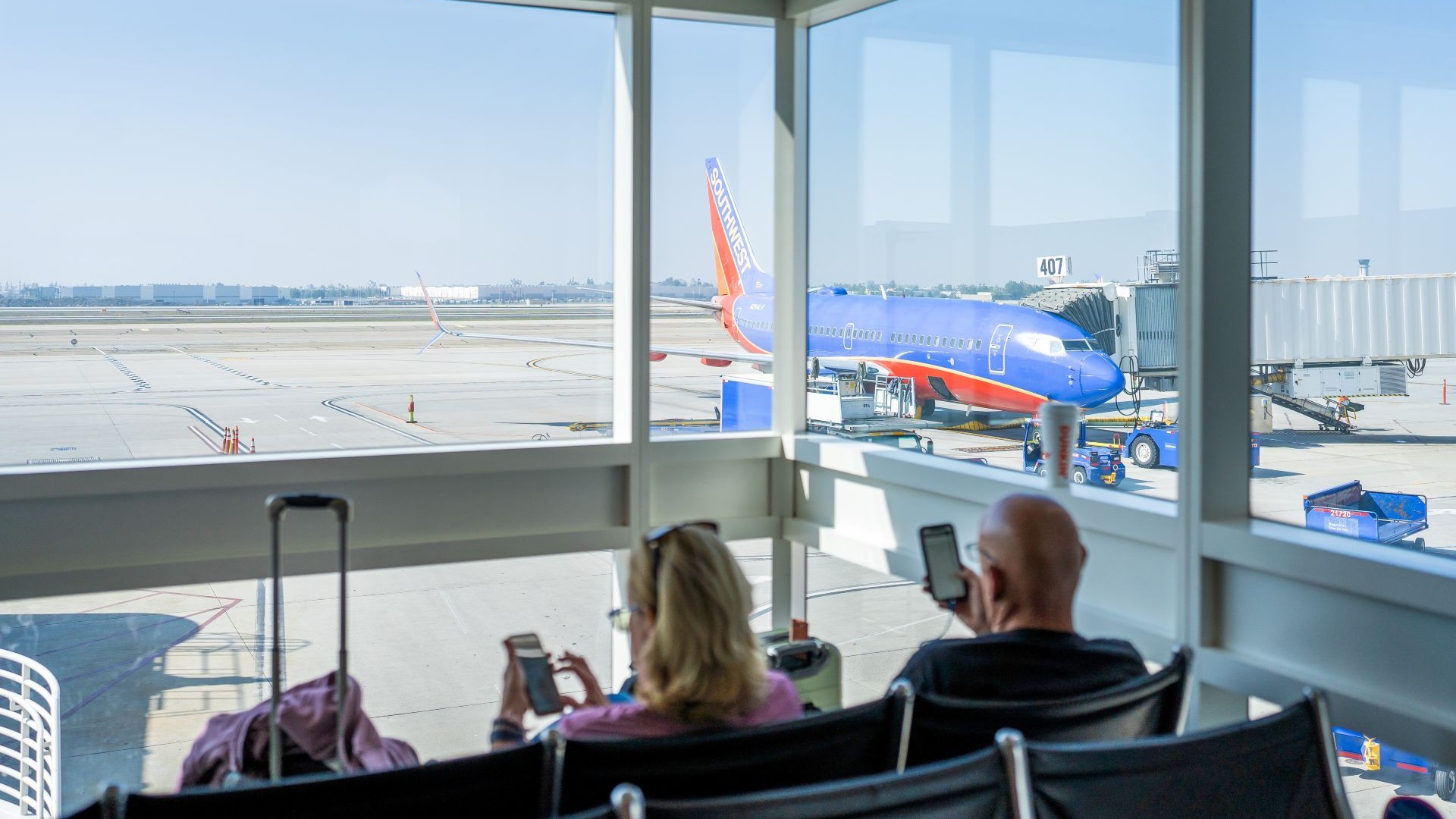 A couple wait in Terminal 4 with a Southwest plane in the background is ready for boarding