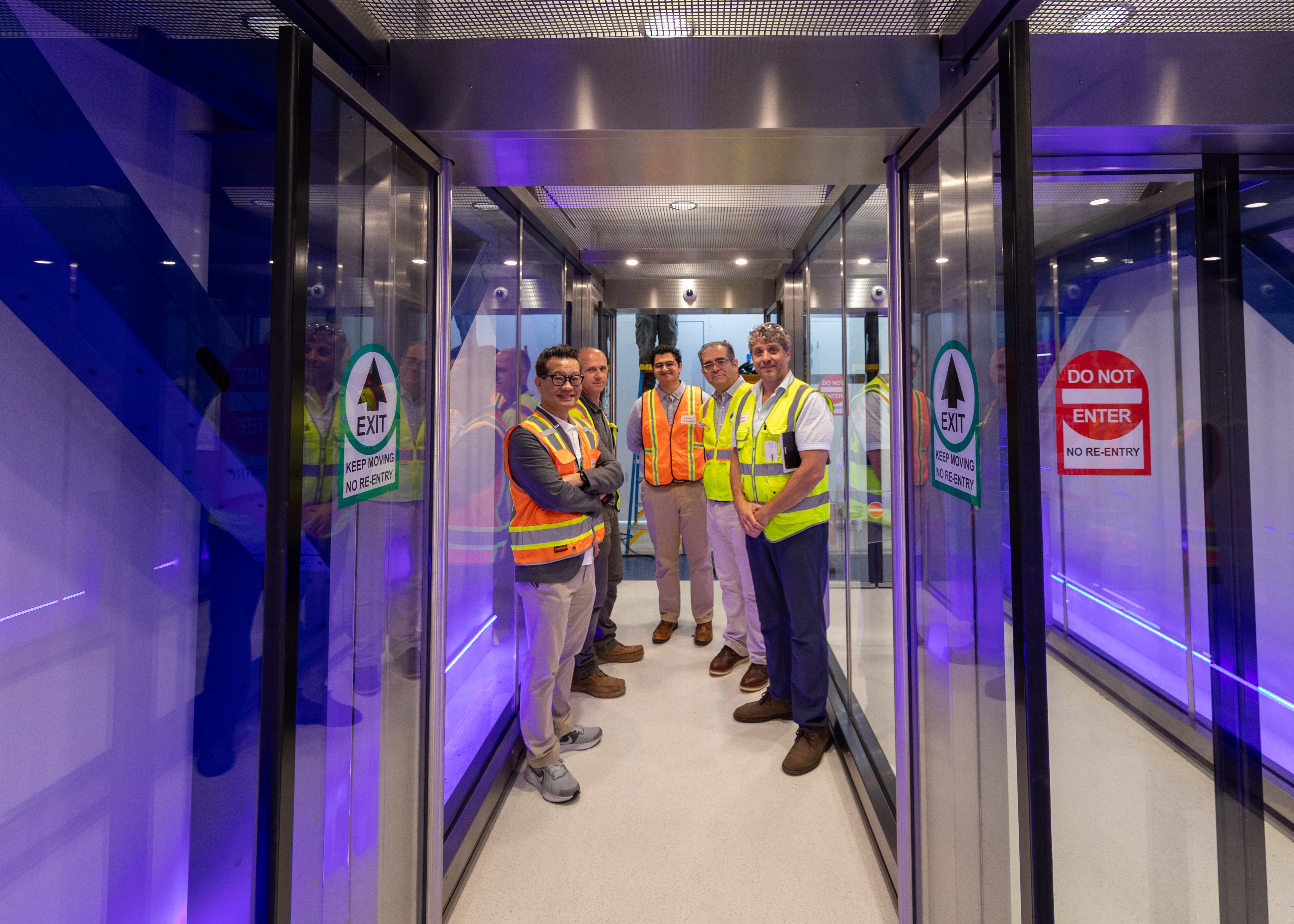 Modern airport corridor with construction workers, purple LED lighting and glass doors
