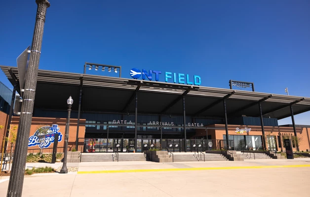 Modern glass-fronted building with "ONT FIELD" signage against clear blue sky