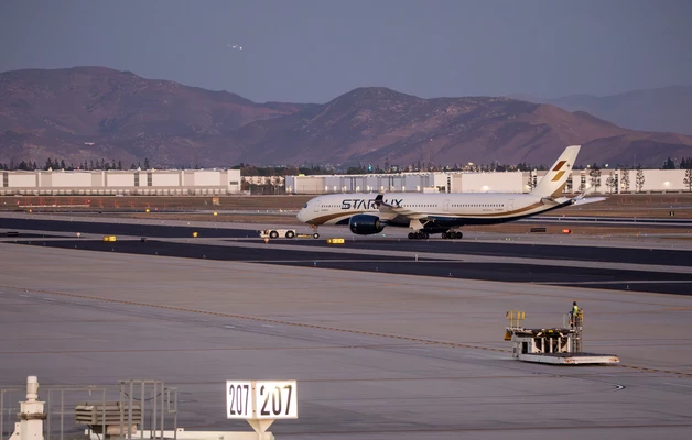 Large commercial aircraft on airport tarmac with mountains in background at dusk