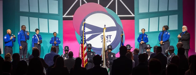 Stage performance with colorful lighting, audience silhouettes, and large circular projection on backdrop.