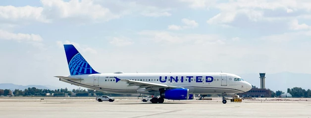 United Airlines jet on airport tarmac with blue and white livery.