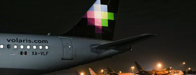 Airline tail with colorful geometric logo on aircraft at night.