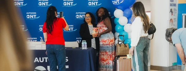 People gathered at a ONT booth or event space with branded blue backdrop.