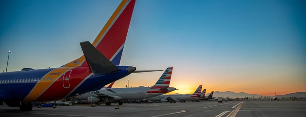 Southwest Airlines plane on airport tarmac at sunset with other aircraft lined up.