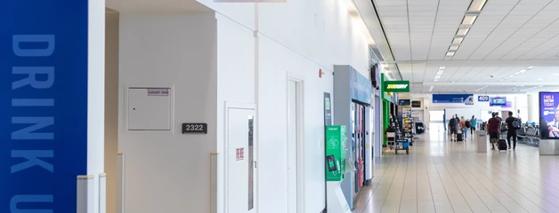 Interior of an airport corridor with blue signage for restrooms and drinking fountain.