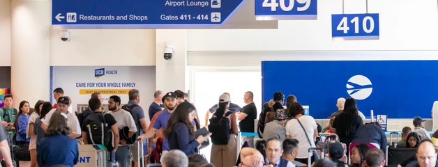 Crowded airport terminal with passengers queuing at gates 409 and 410