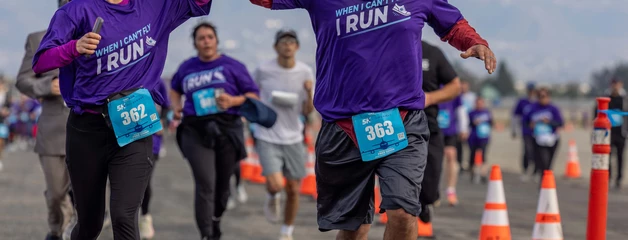 Runners in purple shirts giving high-fives duringa 5k event at Ontario International Airport