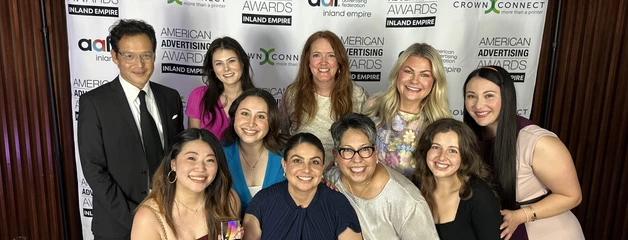 A group photograph of 10 people posing in front of event banners and logos.