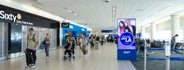 Airport terminal with travelers walking past gate 207 and retail shops