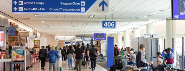 Airport terminal with passengers walking past gates and seating areas
