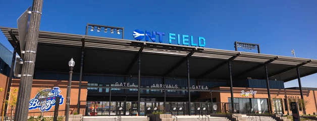 Modern glass-fronted building with "ONT FIELD" signage against clear blue sky