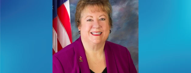 Commissioner Debra Porada smiling headshot with an American flag in the background.