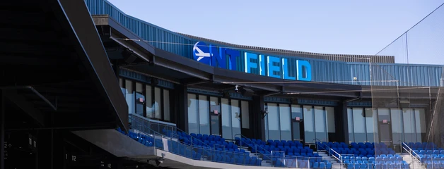 Stadium press box with blue "Field" signage above empty grandstand seating.