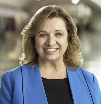 Professional headshot of Karen Kavanagh with blonde hair in a blue blazer smiling at the camera.