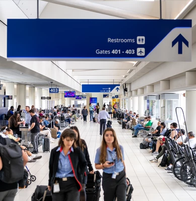 Busy airport terminal with passengers waiting at departure gates.