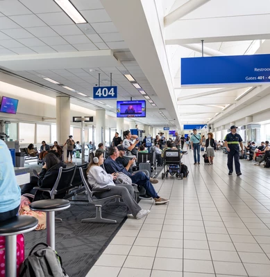 Busy airport terminal with travelers waiting at gates.