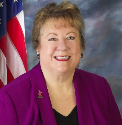 Commissioner Debra Porada smiling headshot with an American flag in the background.