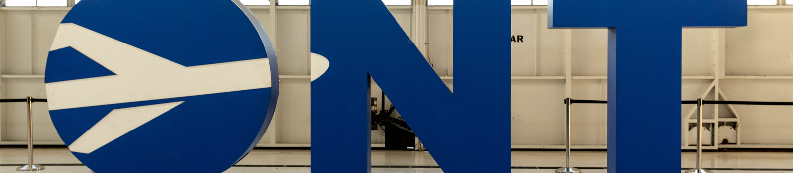 Blue ONT logo with circular emblem displaying a white arrow on display in an interior space.