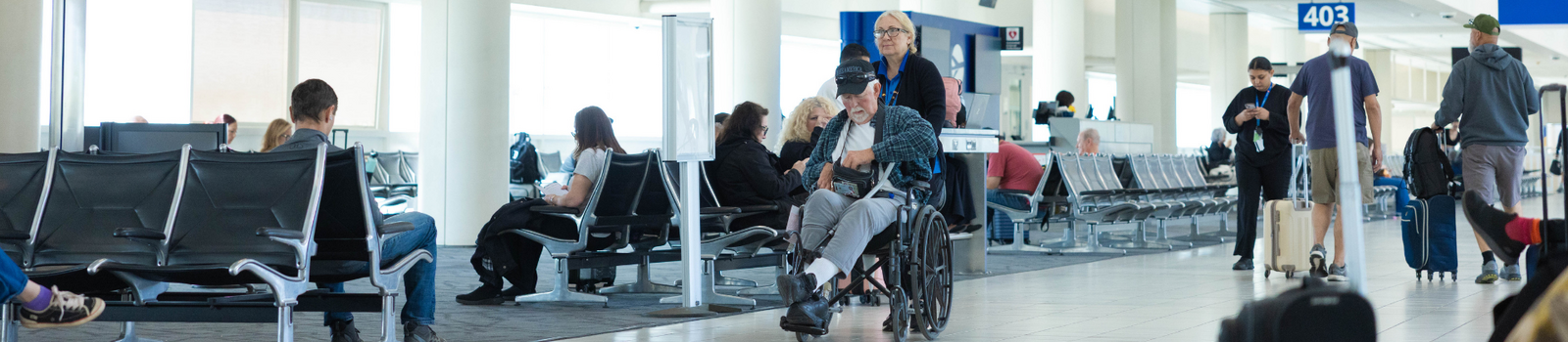 A man in a wheelchair being pushed through the terminal.