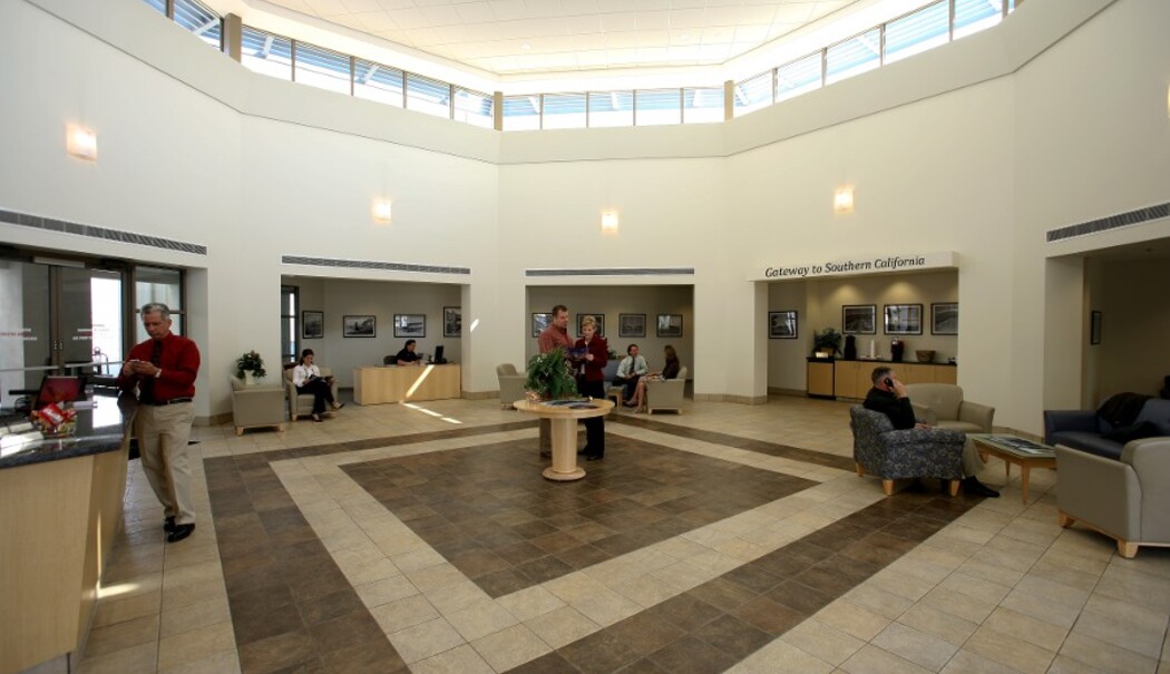 A circular lobby with a high ceiling featuring skylights, reception desk, and seating area.