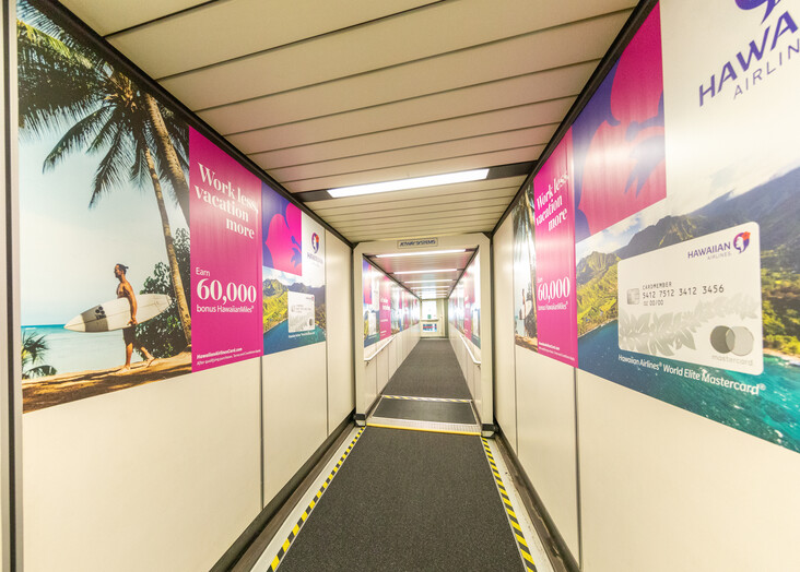 A corridor with pink wall displays and information panels leading to an exit.