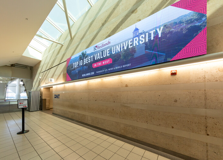 Modern hallway with wooden wall featuring a colorful Monash University banner mounted above.
