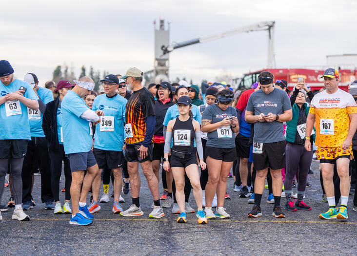 A crowd of people wait at the start line to run the 5K with lots of blue ONT shirts and workout gear on.